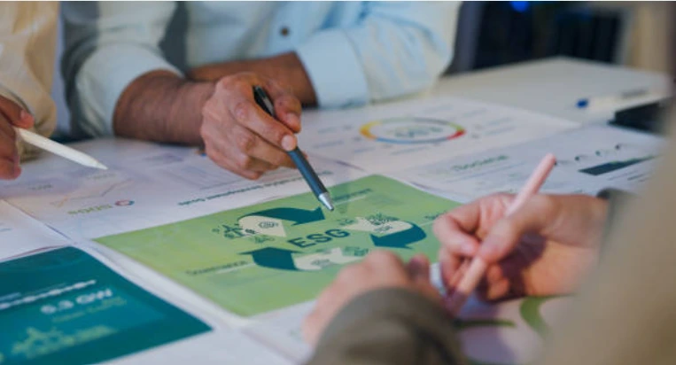 Personas analizando documentos sobre sostenibilidad y criterios ESG en una mesa de trabajo.